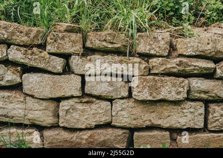 Recinzione di pietra, coltivata con muschio e erba. Tessitura di pietra. Architettura obsoletata Foto Stock