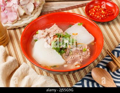 Costolette di maiale e zuppa di rafano una ciotola con cucchiaio e bastoncini di covata isolati sulla vista laterale mat su tavola di legno taiwan cibo Foto Stock