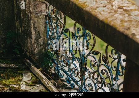 Vista sulle barre decorative in ferro battuto del vecchio balcone in pietra. Area abbandonata. Architettura antica. Foto Stock