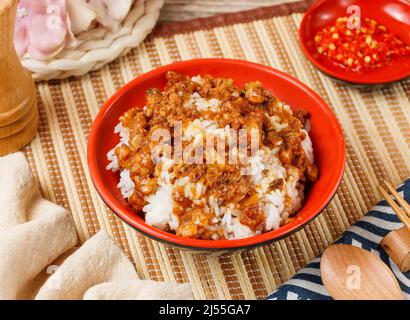 Riso di maiale brasato firmato in una ciotola con cucchiaio e bastoncini di covone isolato sul lato del tappeto vista sul tavolo di legno taiwan cibo Foto Stock