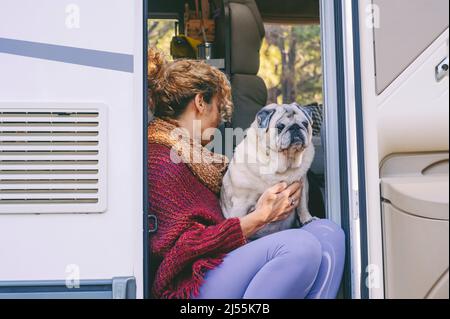 Vivere fuori stile di vita griglia con la donna e il suo cane migliore amico seduto e rilassante sulla porta della moderna camper a motore casa. Peo di vanlife alternativo Foto Stock