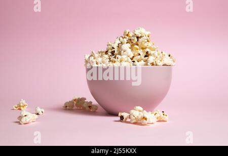 Popcorn in una ciotola rosa su sfondo rosa Foto Stock