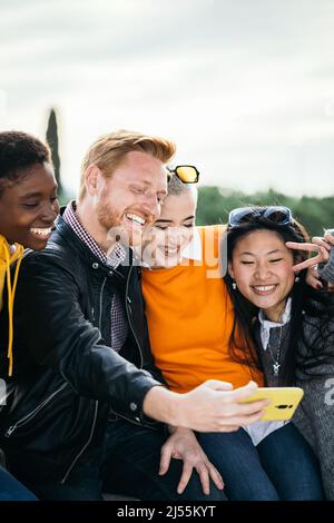 Felice gruppo millenario di persone multirazziali che prendono insieme selfie all'aperto Foto Stock