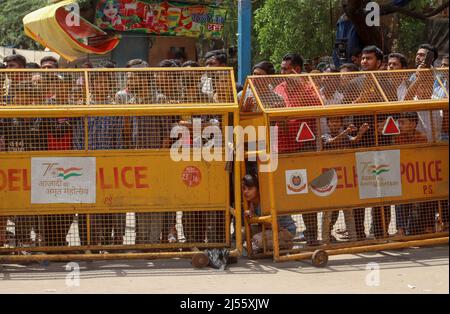 I residenti locali si trovano dietro le barricate della polizia, mentre un bulldozer demolisce una struttura illegale durante un'unità anti-incrostazione condotta dalla North Delhi Municipal Corporation (MCD) nella zona di Jahangirpuri. Foto Stock