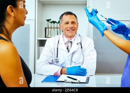 infermiere che prepara l'iniezione ad una paziente in medico ospedaliero che guarda al lato dell'industria infermieristica sanitaria Foto Stock