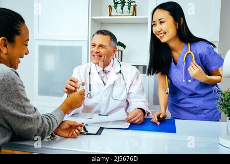 sorridente medico felice e infermiere professionista che danno spray nasale a paziente femminile in ospedale consultazione industria sanitaria Foto Stock