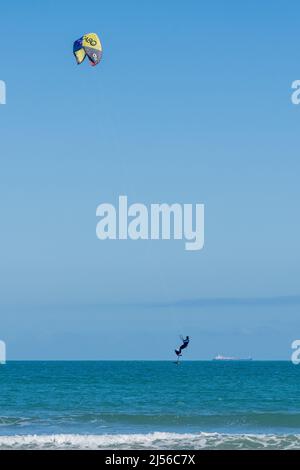 Un kite surfer su un aliscafo bordo salta fuori dall'acqua mentre kiting nel golfo del Messico a South Padre Island, Texas. Sullo sfondo è un lar Foto Stock