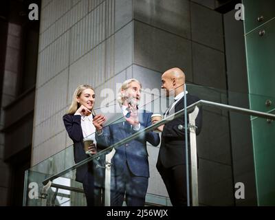 Multinazionale e multietnica popolazione aziendale a discutere di business utilizzando digitale compressa in un ufficio moderno edificio, basso angolo di visione. Foto Stock