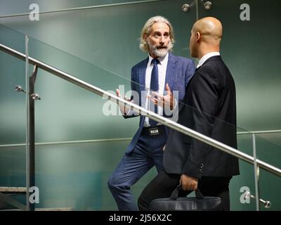 uomini d'affari caucasici e latini che parlano chiacchierando mentre camminano sulle scale nell'edificio moderno degli uffici Foto Stock