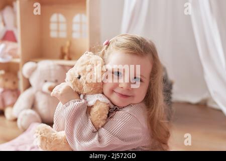 Ragazza che gioca nella stanza dei bambini. Bambino con orso giocattolo. Sala giochi per bambini. Giocattoli didattici. Sviluppo precoce del bambino Foto Stock