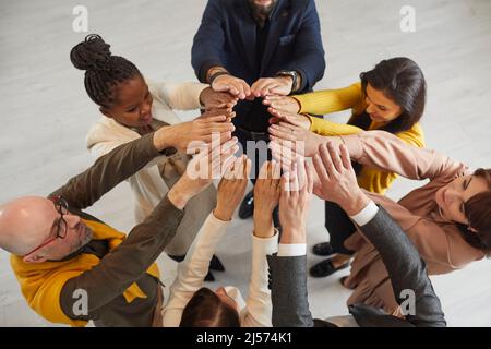 Vista dall'alto della squadra multirazziale di gente felice di affari che mette le loro mani insieme Foto Stock