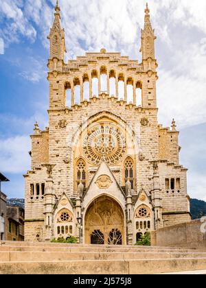 Fotografia della facciata in stile gotico della chiesa di Sant Bartomeu a Soller con ornamenti con rosone. Scala in primo piano. Foto Stock