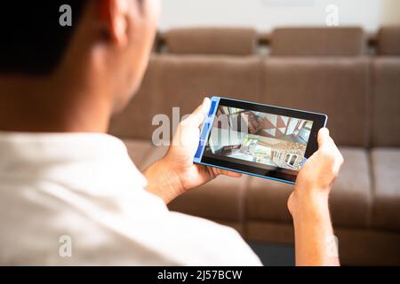 La spalla del proprietario di casa controlla le riprese della telecamera tvcc su tablet digitale intelligente a casa - concetto di sicurezza, tecnologia e sorveglianza. Foto Stock