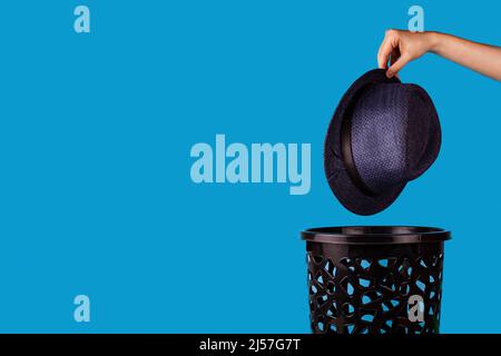 Il cappello viene gettato nel cestino. Per spazio di copia per i designer su sfondo blu. Foto Stock