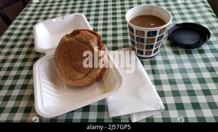 BANGOR. GWYNEDD. GALLES. 06-26-21. La stazione ferroviaria buffet un caffè da asporto e pane di salsiccia calda, servito su una tovaglia lino verdeggiante. Foto Stock