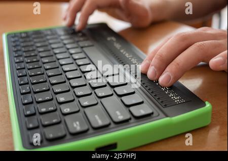 Un uomo cieco utilizza un computer con un display Braille e una tastiera per computer. Dispositivo incluso. Foto Stock