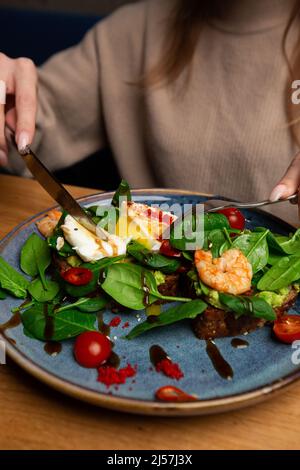 Pane di grano saraceno toasts con un uovo in camicia, un avocado a fette, un gamberetti, pomodori e lattuga. Menu dietetico. Disposizione piatta Foto Stock
