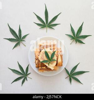 Rotolo dolce con olio di marijuana su piatto bianco. Cucina di cannabis. Disposizione dei deliziosi dessert, vista dall'alto da vicino. Foto Stock