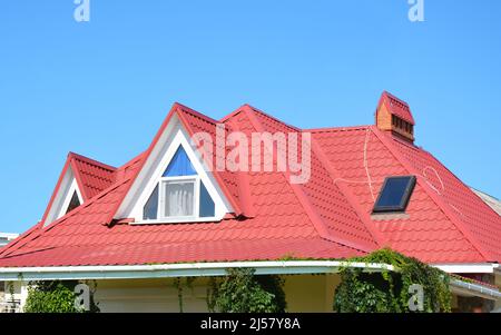 Costruzione di tetti a valle e a gable con finestre sottotetto, gocciolatoio, impermeabilizzazione. Sistema di grondaia per tetto, lucernario su tegole in metallo della casa attico Foto Stock