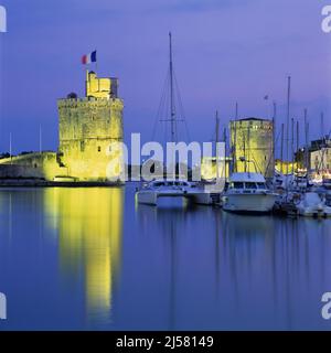 Il vecchio porto con le torri Tour de la Chaine e St Nicolas illuminate al tramonto, la Rochelle, Nouvelle Aquitaine, Atlantic Coast, Francia, Europa Foto Stock