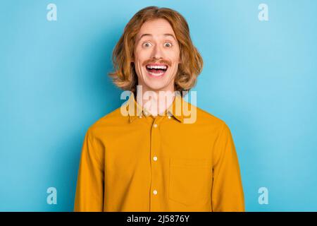 Ritratto di attraente ragazzo allegro pazzo a capelli lunghi avendo divertimento grande notizie isolato su sfondo blu brillante Foto Stock