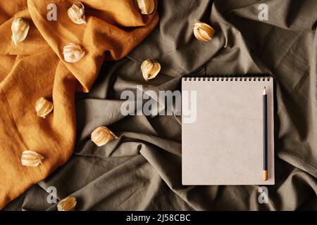 Vista superiore del taccuino bianco con rilegatura a spirale e matita posta su tessuti grattati Foto Stock