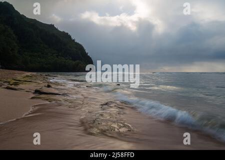 Le onde si lavano su KE'e Beach nel Ha'ena state Park a Kauai, Hawaii. Le nuvole di tempesta oscurano la costa di Na Pali in lontananza. Foto Stock