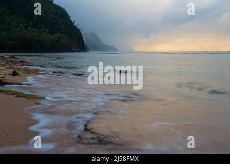 Le onde si lavano su KE'e Beach nel Ha'ena state Park a Kauai, Hawaii. Le nuvole di tempesta oscurano la costa di Na Pali in lontananza. Foto Stock