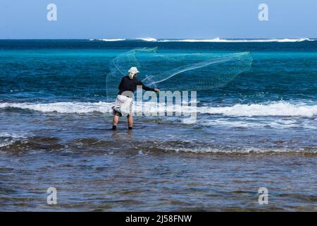 Un pescatore getta la sua rete nel surf su Haena Beach sull'isola di Kauai, Hawaii, Stati Uniti. Foto Stock