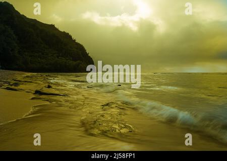 Le onde si lavano su KE'e Beach nel Ha'ena state Park a Kauai, Hawaii. Le nuvole di tempesta oscurano la costa di Na Pali in lontananza. Foto Stock