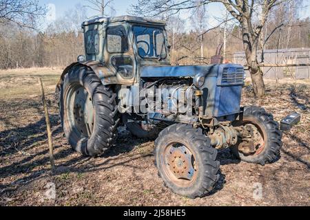Vecchio trattore russo arrugginito in un cantiere, masheria agricola in Unione Sovietica, fabbricato in URSS Foto Stock