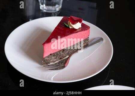 Pezzo di famosa torta di semi di papavero con mousse di lamponi di origine austriaca servito con panna montata e tazza di caffè in vecchio classico caffè-ristorante in Foto Stock