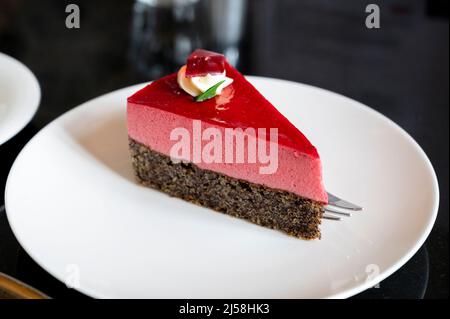 Pezzo di famosa torta di semi di papavero con mousse di lamponi di origine austriaca servito con panna montata e tazza di caffè in vecchio classico caffè-ristorante in Foto Stock