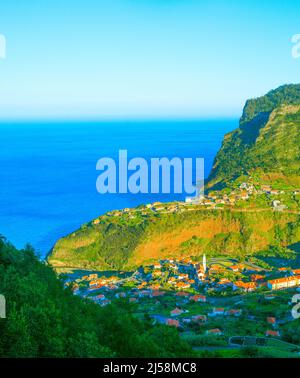 Paesaggio con Maderia villaggio, montagne e oceano al tramonto. Isola di Madeira, Portogallo Foto Stock