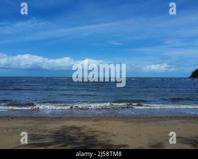 Vista delle onde che si infrangono sulla spiaggia con il cielo blu Foto Stock