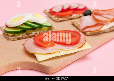 Diversi tipi di pane integrale con Prato, pomodoro, Rasth, cetriolo e formaggio. Colazione facile. Dieta alimentare. Panini veloci e sani. Croccante con gustoso ripieno. Snack dietetico sano Foto Stock