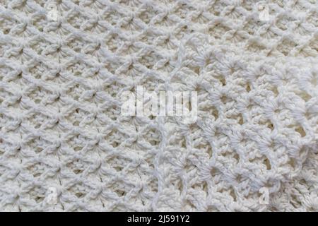 Primo piano di una vista dall'alto di una coperta di cotone bianco con un originale motivo a punto a crochet goffrato con una punta piegata verso il centro, creat fatto a mano Foto Stock