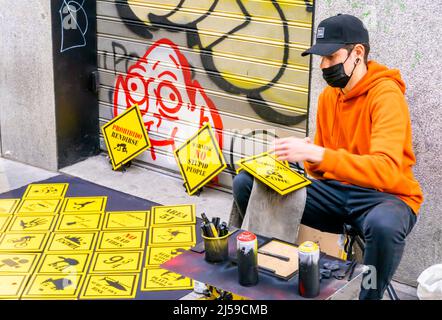 Artista di strada in maschera di pittura giallo cartelline stradali rombiche e venderli a terra in c Fuencarral, Malasana, Madrid, Spagna Foto Stock