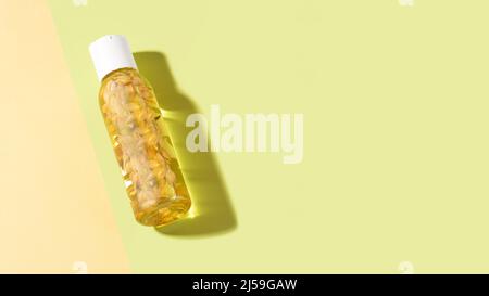 Una bottiglia di olio essenziale di gelsomino con fiori di gelsomino all'interno giacenti su sfondo verde chiaro. Cosmetici per bagni corpo. Fitoterapia, aromaterapia Foto Stock