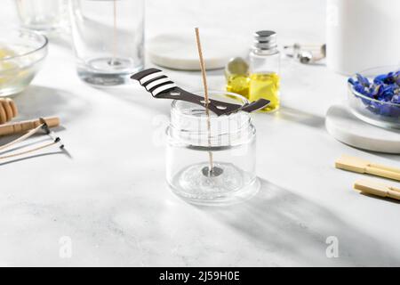 Set di strumenti per candele naturali eco-friendly di cera di soia, stoppino, profumo, olio essenziale su un tavolo di marmo. Processo di fabbricazione. Fai da te alla moda. Hobby artigianale, Foto Stock