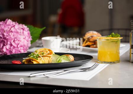Salate funghi fatti in casa e Spinach verdi Crepes con formaggio e tazza di tè isolato su sfondo grigio. Cibo fatto in casa. Colazione gustosa. Selettivo per Foto Stock