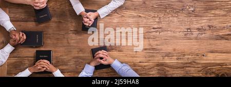 Elevato angolo di visione delle persone di pregare le mani sulla Sacra Bibbia Foto Stock