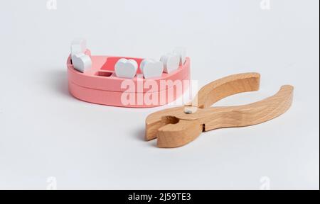 Pinza e mandibola umana in legno. Estrazione dei denti, procedura di trazione. Problemi dentali, malattia periodontale, concetto di igiene orale. Giocattolo per bambini. Foto di alta qualità Foto Stock