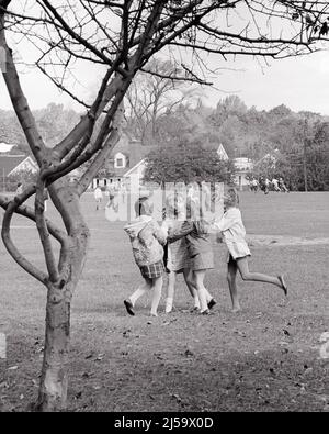 1970S GRUPPO DI QUATTRO RAGAZZE ANONIME IN UN HUDDLE CHE GIOCANO INSIEME NEL CAMPO DI GIOCO DELLA SCUOLA DURANTE LA RECESS - J12731 HAR001 HARS CRICCA ANONIMA SCUOLA GIOVANI ETNIA BIANCO E NERO ETNIA CAUCASICA HAR001 VECCHIO STILE Foto Stock