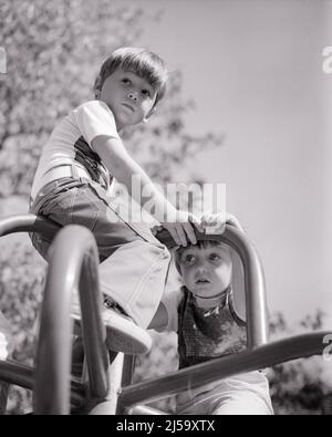 1970S RAGAZZO E RAGAZZA ARRAMPICATA SULLA GIUNGLA PALESTRA - J13856 HAR001 HARS COPIA SPAZIO AMICIZIA FULL-LENGTH MEZZA LUNGHEZZA PERSONE MASCHI RISCHIO FRATELLI FIDUCIA SORELLE ATTIVITÀ B&W BENESSERE FISICO FORZA CORAGGIO E RECESSO RICREAZIONE FRATELLO CONCETTUALE FLESSIBILITÀ MUSCOLARE COOPERAZIONE CRESCITA GIOVANI RELAX TOGETHERNESS NERO E BIANCO ETNIA CAUCASICA HAR001 VECCHIO STILE Foto Stock