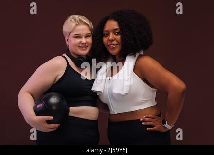Due femmine più grandi con accessori per il fitness Uniti su sfondo marrone Foto Stock