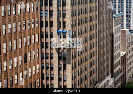 Team di lavoratori che sostituiscono mattoni su un ufficio edificio facciata mentre si lavora in un carro sospeso 15 Stories Up , NYC, USA, 2022 Foto Stock