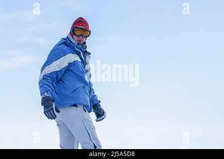 Snowboarder si erge sulle piste della montagna con uno snowboard in attrezzatura da sci Foto Stock