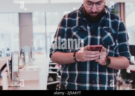 I responsabili di ufficio lavorano nello spazio di coworking utilizzando lo smartphone che analizza le tendenze del mercato online, un uomo concentrato che legge le notizie finanziarie o naviga Foto Stock