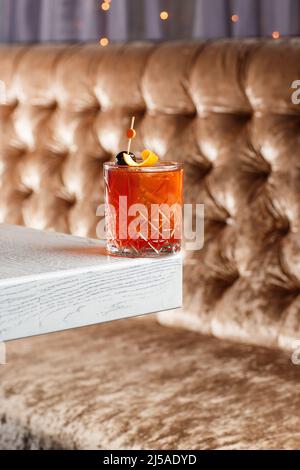 Bicchiere di gustoso cocktail di whiskey fresco e forte decorato con buccia d'arancia sullo sfondo luminoso. Foto Stock